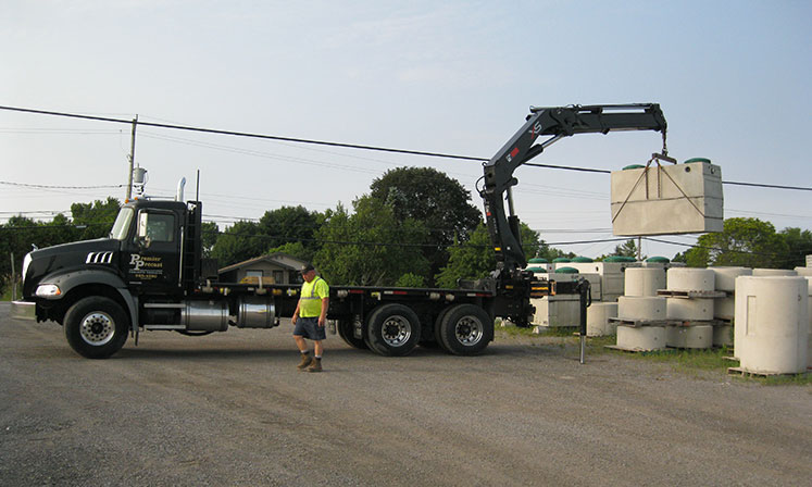 truck in yard carrying precast concrete with worker standing in front