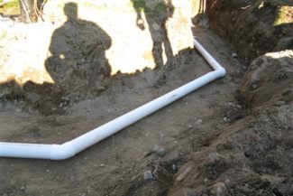 plastic septic pipe uncovered in the ground