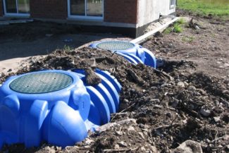 plastic septic holding tanks on ground in back of house
